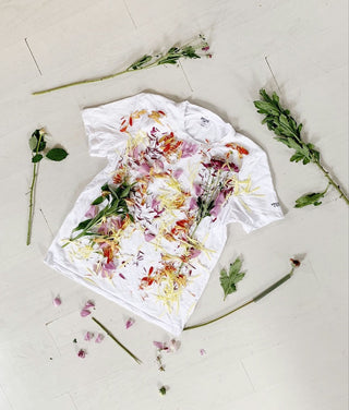 White tshirt laid flat with flower petals and stems laid on top. Image by Anna Sullivan via Upsplash.