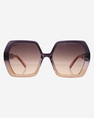 Oversized hexagonal sunglasses with a translucent dark purple frame and a brown-to-clear gradient lens, shown against a light gray background.