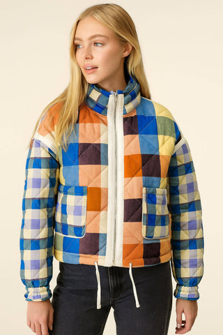 Person wearing a colorful quilted jacket on a beige background