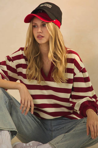 Woman wearing a red and white striped shirt and black cap with red brim.