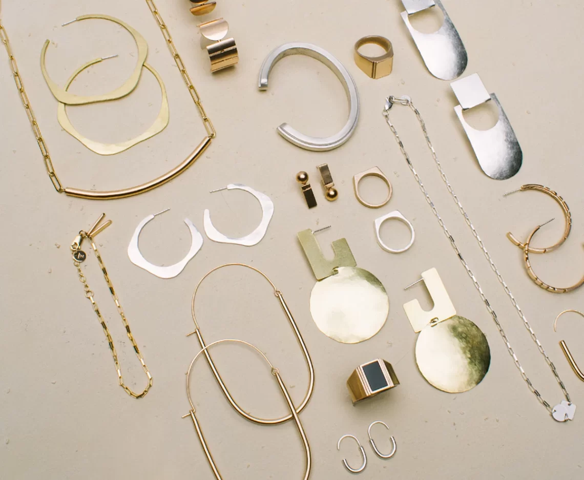 Display of a variety of handmade gold and silver jewellery on a neutral, flat background