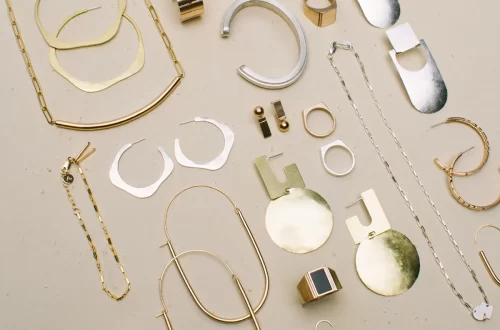 Display of a variety of handmade gold and silver jewellery on a neutral, flat background