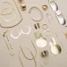 Display of a variety of handmade gold and silver jewellery on a neutral, flat background
