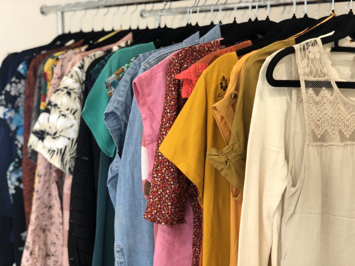 Clothes rack displaying many colorful women's or femme tops.