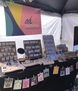 Market stall displaying jewellery and greeting cards.