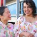 Two people smile joyfully wearing Khòlò's colourful clothing.